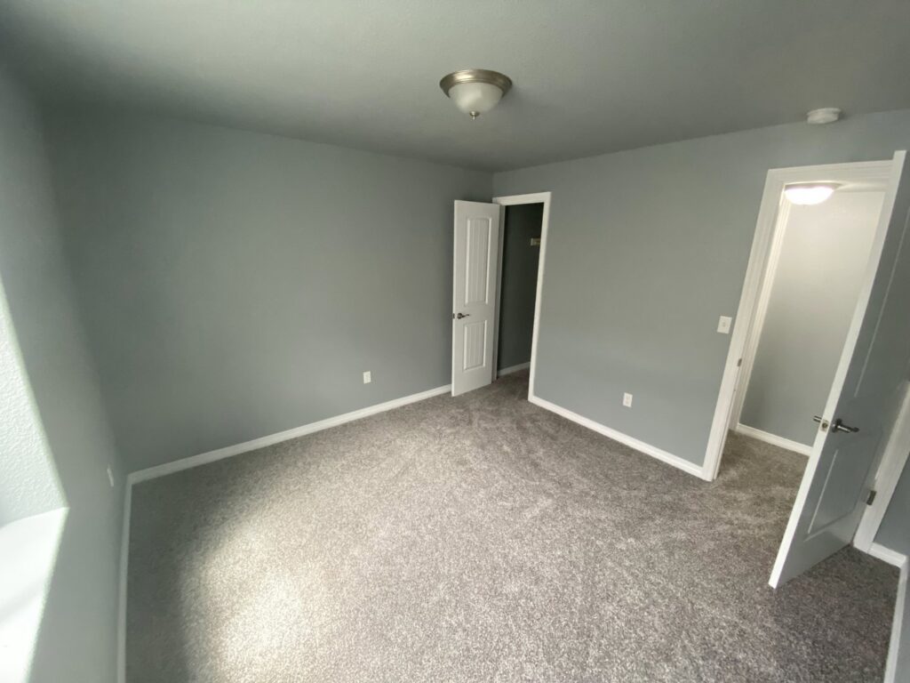 A newly painted bedroom with fresh grey carpet by Advanced Remodeling Services in Elbert, CO.
