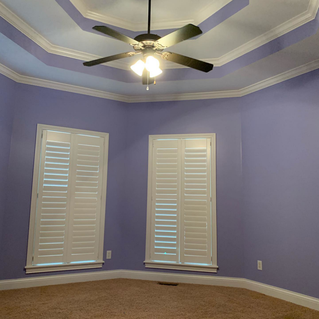A freshly painted bedroom with purple walls, white trim, and a ceiling fan by Wilder Painting, LLC in Quincy, MA