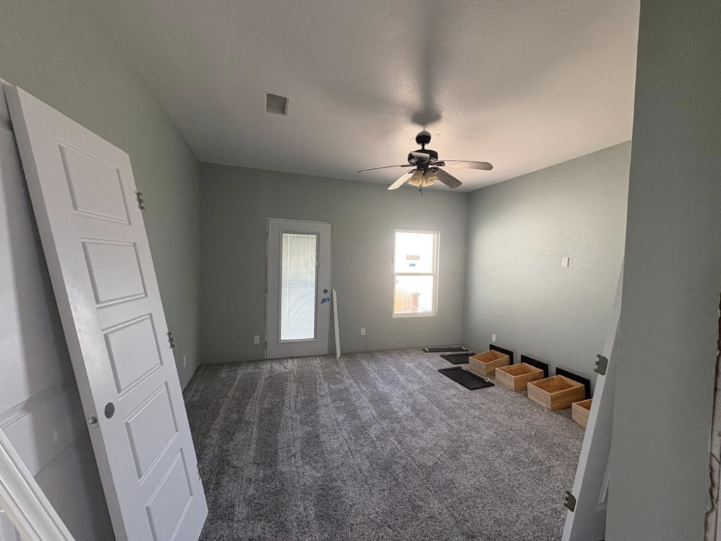 A remodeled bedroom with new carpet, painted walls, and a newly installed ceiling fan by EJL Construction, LLC in Roswell, NM.