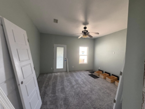A remodeled bedroom with new carpet, painted walls, and a newly installed ceiling fan by EJL Construction, LLC in Roswell, NM.