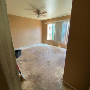 A bedroom undergoing renovation with an exposed subfloor and ceiling fan by Premier Home Services in Fullerton, CA
