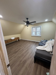 A newly renovated bedroom featuring laminate flooring, a ceiling fan, and fresh paint by T-N-T Mechanical in Westland, MI.