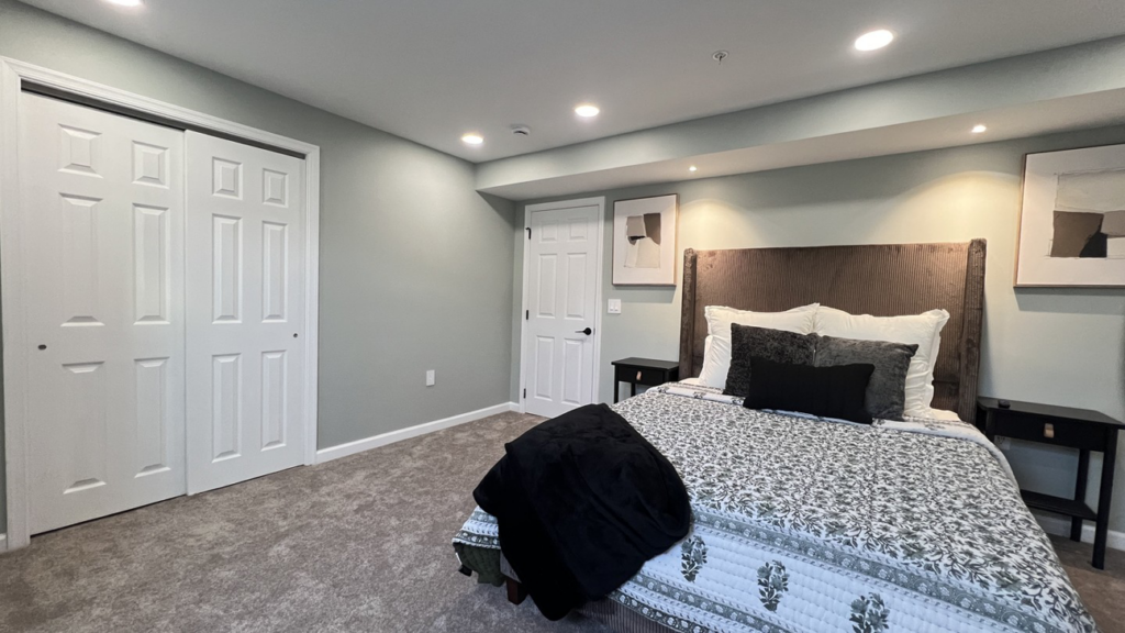 A renovated bedroom featuring new carpet, freshly painted walls, and white bi-fold closet doors by Home Style Improvement in Frederick, MD.