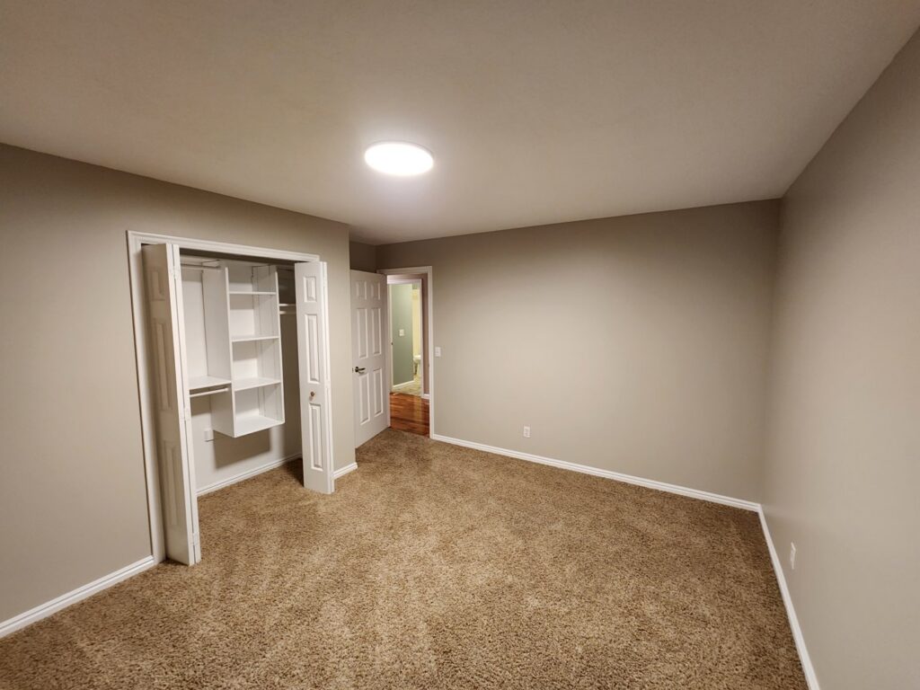 A newly renovated bedroom featuring fresh paint, new carpet, and installed closet shelving by Branham Handyman in Salt Lake City, UT