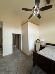 A bedroom showcasing new trim work and a recently installed ceiling fan by M Squared Construction LLC in Tonganoxie, KS.