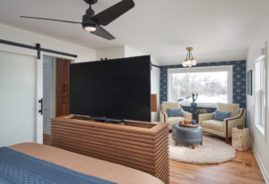 A modern bedroom featuring a custom TV lift cabinet, ceiling fan, and sliding barn door installed by EdgeWork Design Build in Minneapolis, MN.