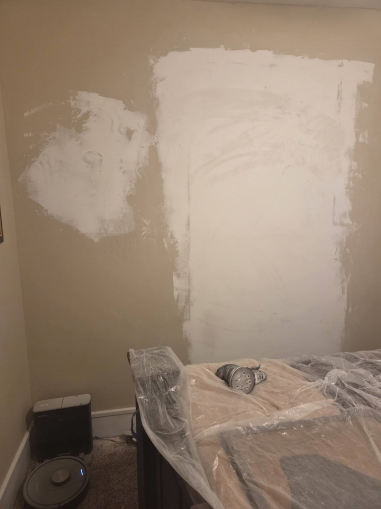 A bedroom wall undergoing repair and sanding, showing handyman services by Joel's flooring & Handyman services in Roy, UT.