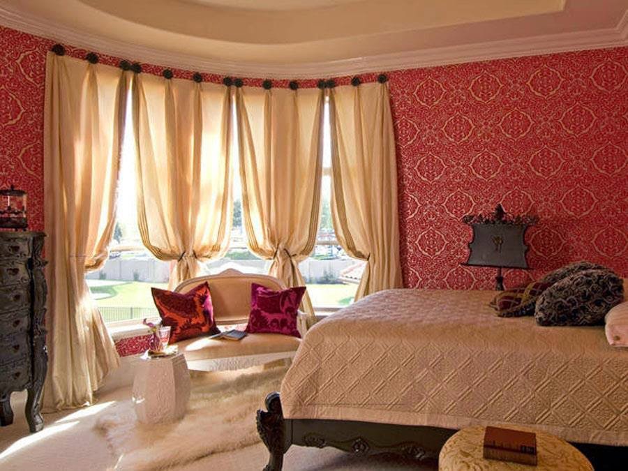 A bedroom featuring newly installed red patterned wallpaper and beige curtains by Surfaces By Design in Duluth, MN.