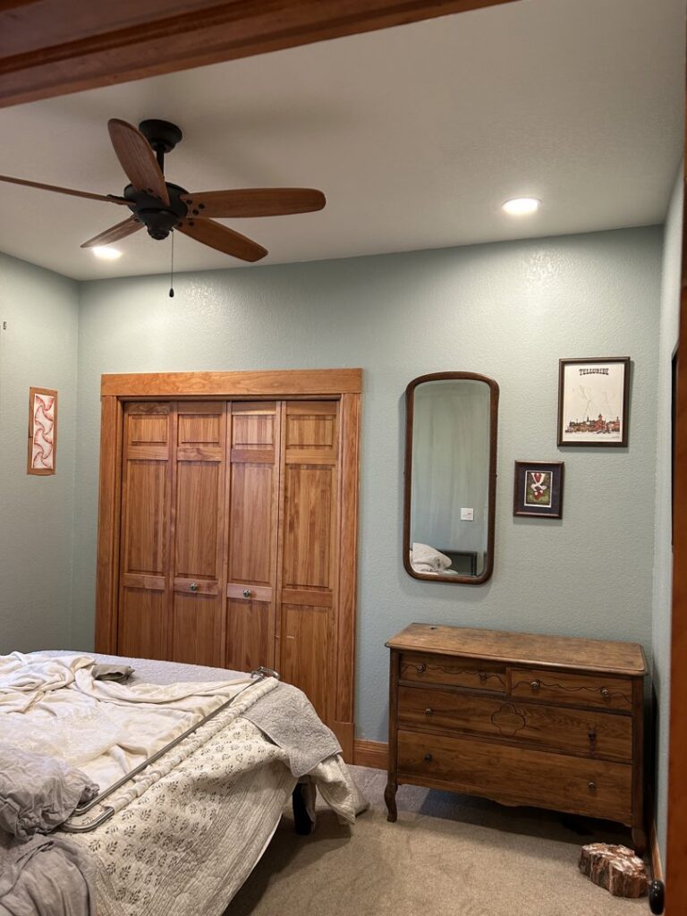 A bedroom featuring a newly installed ceiling fan and wooden bi-fold closet doors, a service by Wam Bam Handyman LLC in Colorado Springs, CO