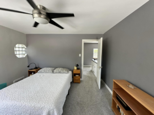 A bedroom with freshly painted gray walls and a new ceiling fan, showcasing work by EJ Drywall Plus in Kearney, NE.