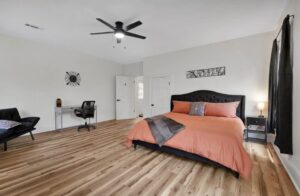 A renovated bedroom with new wood-look flooring and a modern ceiling fan installed by Imperial Access Contracting in Evansville, IN.
