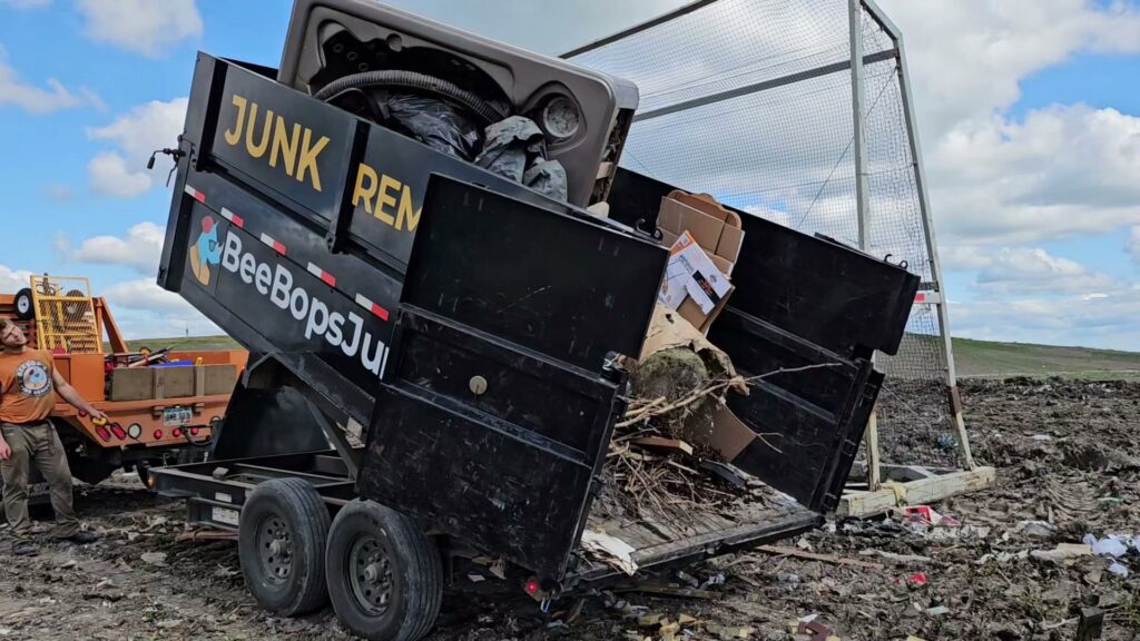 A BeeBop's Junk Removal branded trailer actively dumping a hot tub and debris at a landfill in Sioux Falls, SD.