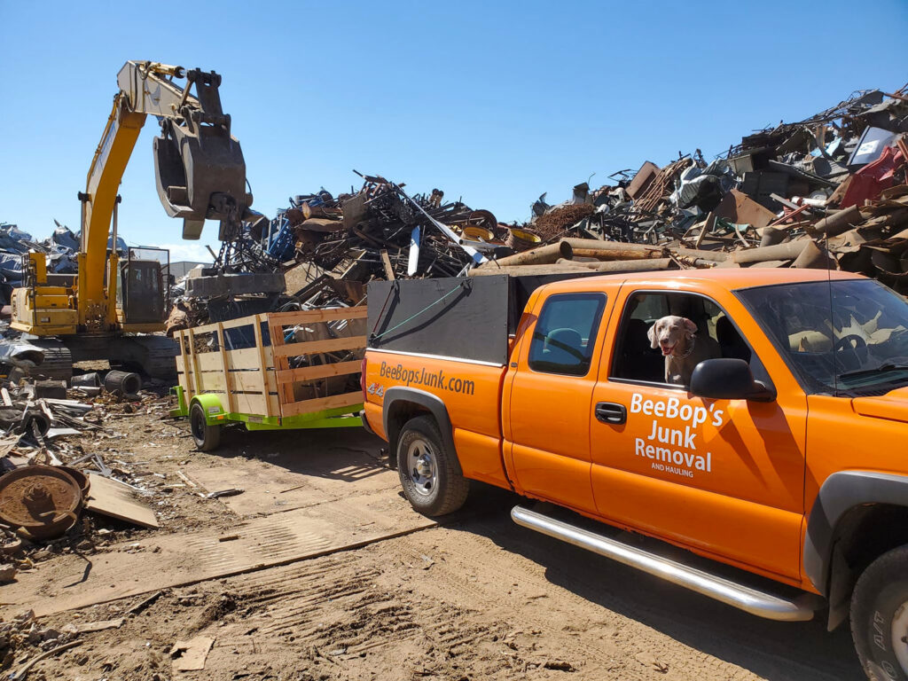 A BeeBop's Junk Removal truck and trailer at a scrap yard, likely disposing of collected junk in Sioux Falls, SD.