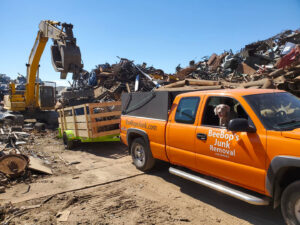 A BeeBop's Junk Removal truck and trailer at a scrap yard, likely disposing of collected junk in Sioux Falls, SD.