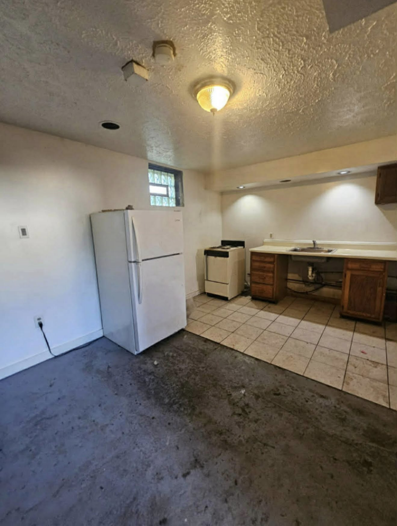 A dirty and outdated basement kitchen with exposed plumbing before renovation by Inside Out Commercial Solutions in Cleveland, OH.