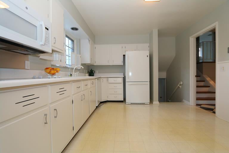 An older kitchen with white cabinets and yellow linoleum flooring, ready for a remodel by KLS Remodel in Cincinnati, OH.