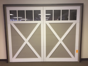 A beige garage door with white X-pattern overlays and top windows, available from Harold Carpenter Overhead Door inc in Oshkosh, WI.