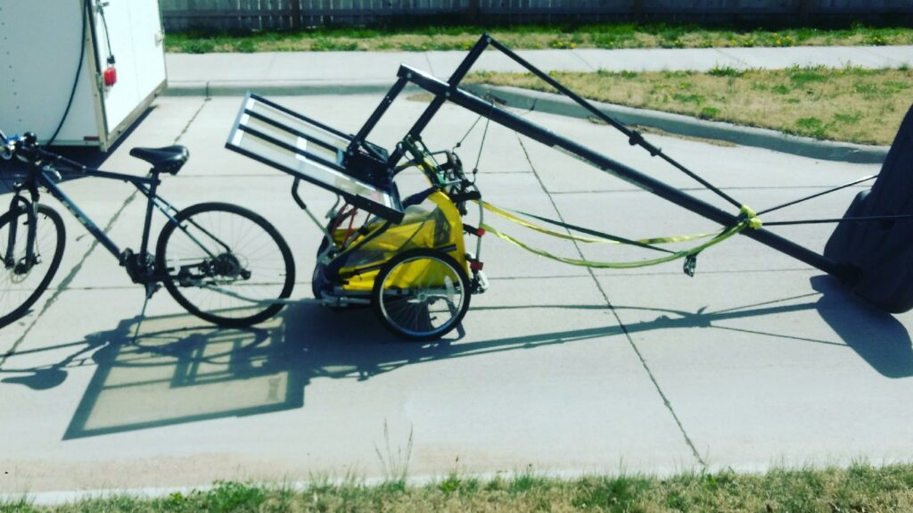 A bicycle towing a trailer with a large, dark item for removal or delivery by TrashnSell in Grand Island, NE