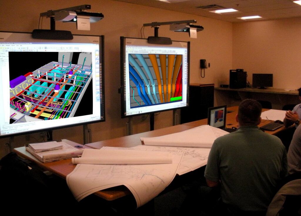 A team meeting reviewing BIM/CAD designs for construction planning, showcasing the detailed work by McKamish, Inc. in Pittsburgh, PA