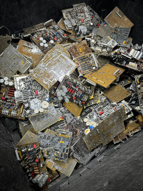 A large bin filled with various gold-colored circuit boards and electronic waste at E-Z Money Recycling LLC in Phoenix, AZ.