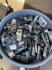 A large bin filled with old, discarded cell phones and mobile devices at E-Z Money Recycling LLC in Phoenix, AZ.