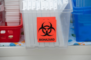 A clear container with a biohazard symbol, filled with medical waste, handled by Med Waste Gone in St. Louis, MO.