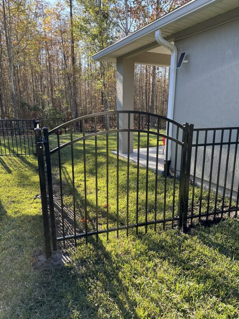 A black aluminum fence with an arched gate installed by NGC FENCE INC in Jacksonville, FL.