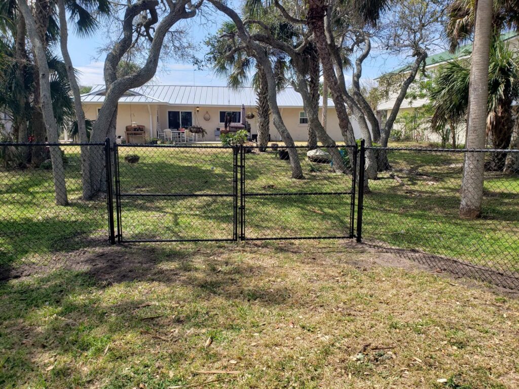 A black chain-link fence with a double gate installed by NGC FENCE INC in Jacksonville, FL.