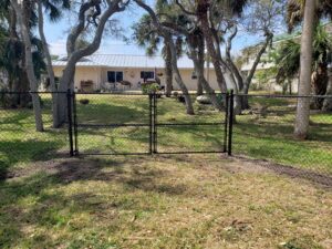 A black chain-link fence with a double gate installed by NGC FENCE INC in Jacksonville, FL.