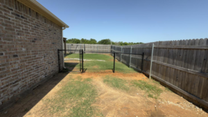Newly installed black chain-link fence with a gate in a backyard by Herron Fencing LLC in Shawnee, OK.