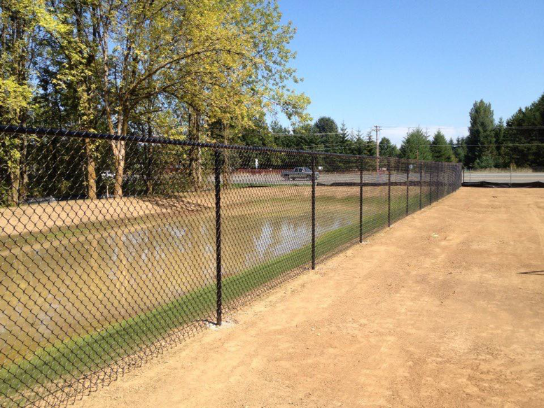 A long black chain-link fence installed along a property line by J & M Fence Co. in Vancouver, WA.