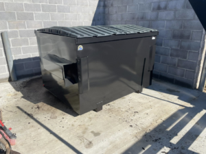 A black commercial dumpster with a flat lid provided by Eagle Industrial Solutions in Louisville, KY.