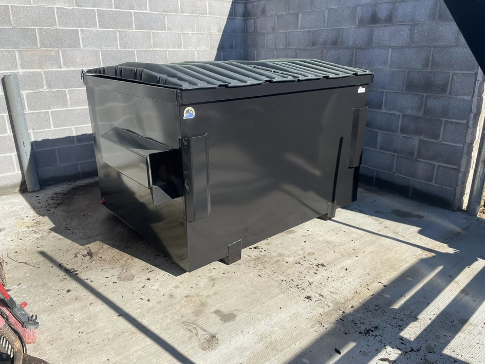 A black commercial dumpster with a flat lid provided by Eagle Industrial Solutions in Louisville, KY.