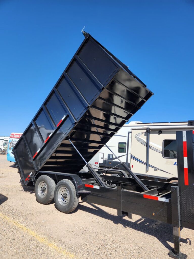 A black dump trailer with its bed raised, in the process of unloading junk for Jigsaw Transport and Waste in Albuquerque, NM.