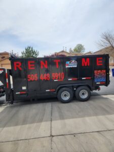 A black dump trailer with 'RENT ME' and the Jigsaw Transport and Waste logo, available for rent in Albuquerque, NM.