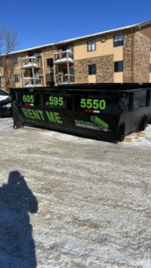 A black dumpster from Waste-Away Dumpsters & Disposal LLC placed outside an apartment complex in Sioux Falls, SD.
