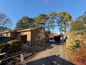 A black dumpster positioned on a residential driveway for junk removal by Great Bridge Bins in Norfolk, VA.