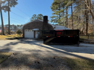 A black dumpster bin placed in a residential driveway by Great Bridge Bins in Chesapeake, VA.