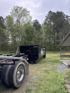 A black Wallburg Disposal Worx LLC dumpster placed in a grassy area for junk removal in High Point, NC.