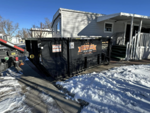 A black roll-off dumpster from Denver Dumpsters placed in front of a residential home in Denver, CO.