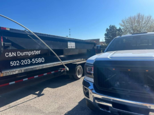 A black dumpster trailer with C&N Dumpster branding hitched to a truck in Louisville, KY