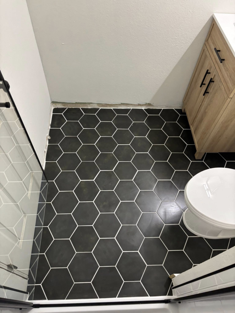 Close-up view of newly installed black hexagonal floor tiles in a bathroom by Abes Pacific Construction in Hillsboro, OR