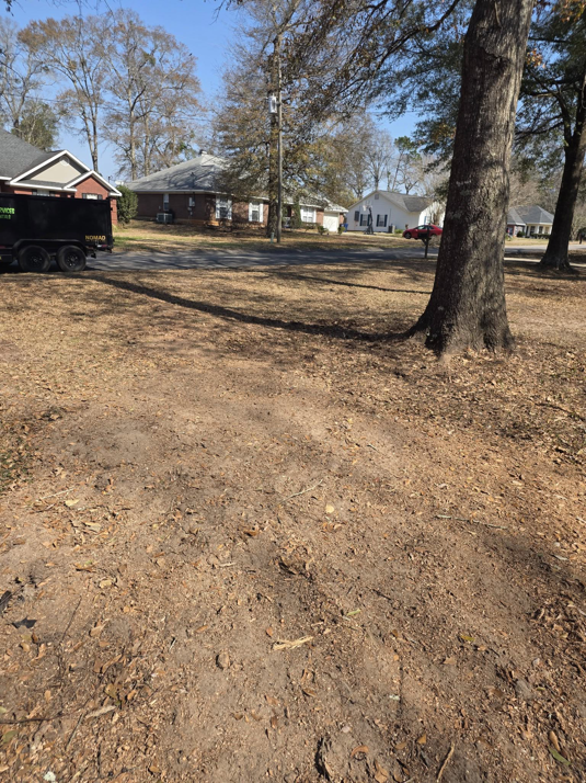 A black junk removal trailer parked on a residential street for Cain's junk removal service LLC in Mobile, AL.