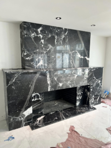 A stunning black marble fireplace surround and mantel installation by Bohannon Custom Tile and Renovation in Virginia Beach, VA.