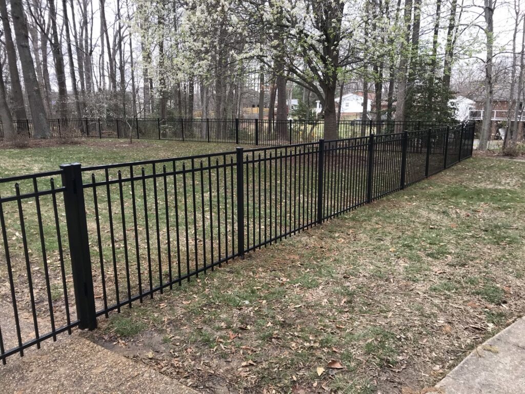 A black metal fence installed in a backyard extending into a wooded area by Premier Fence Company in Glen Allen, VA.