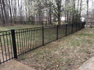 A black metal fence installed in a backyard extending into a wooded area by Premier Fence Company in Glen Allen, VA.