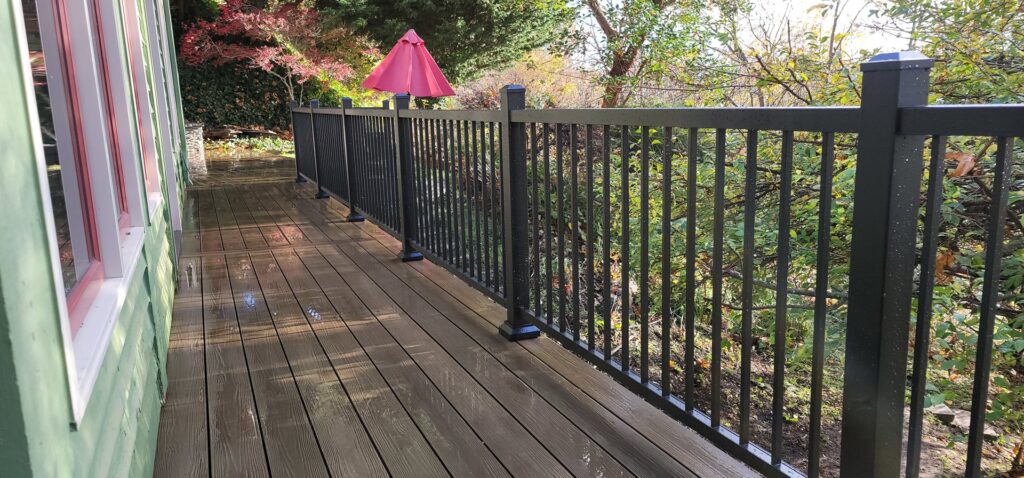 A newly installed black metal railing on a wooden deck by LMS Landscapes & Fence services in Auburn, WA.
