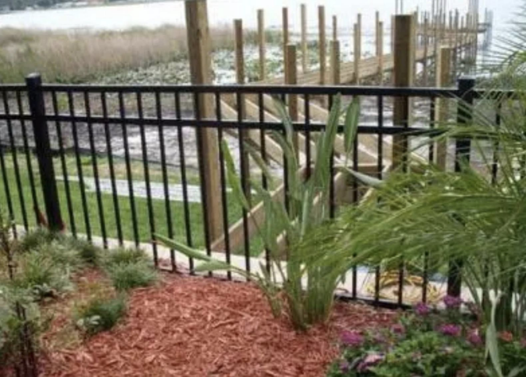 A newly installed black metal fence and a wooden dock by the water, completed by Cover Works in Luling, LA.