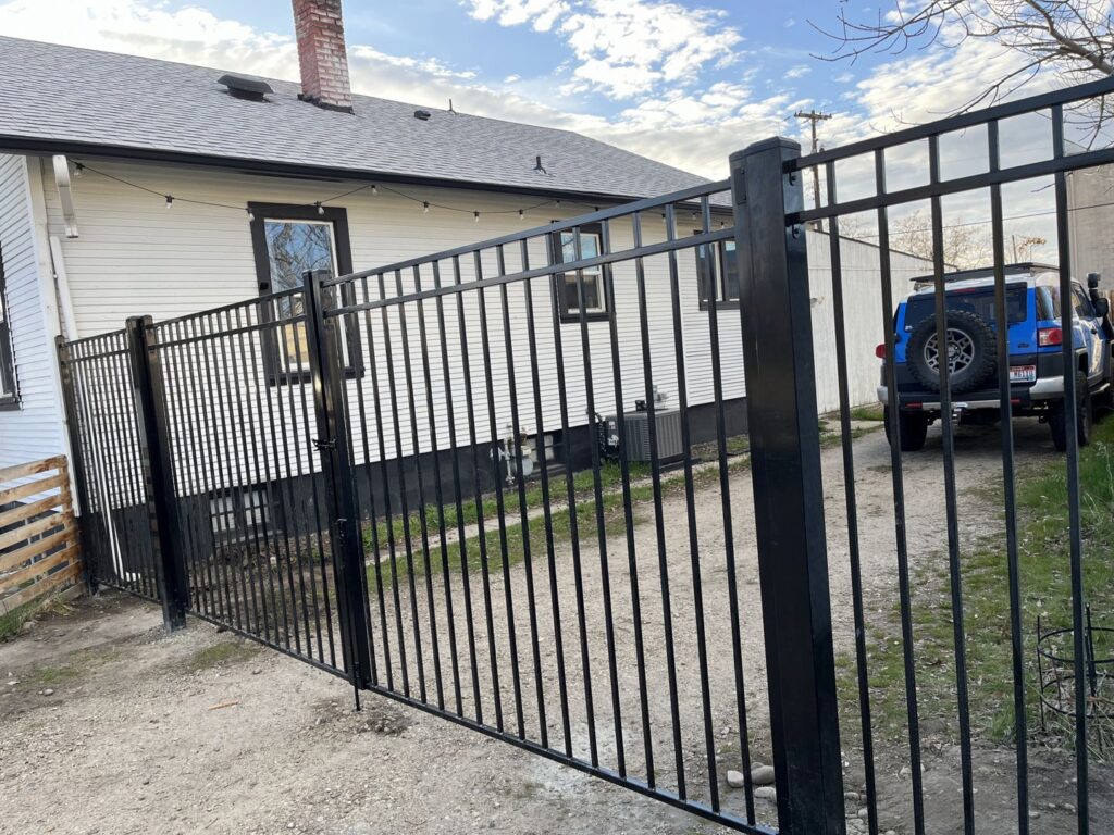 A newly installed black metal fence and gate next to a house, completed by Forever Young Handyman Services in Boise, ID.
