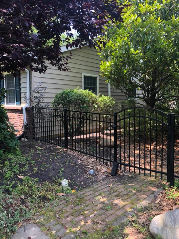 A newly installed black metal fence and gate in a residential garden by Quality Care Home Improvements in Hamilton, NJ.